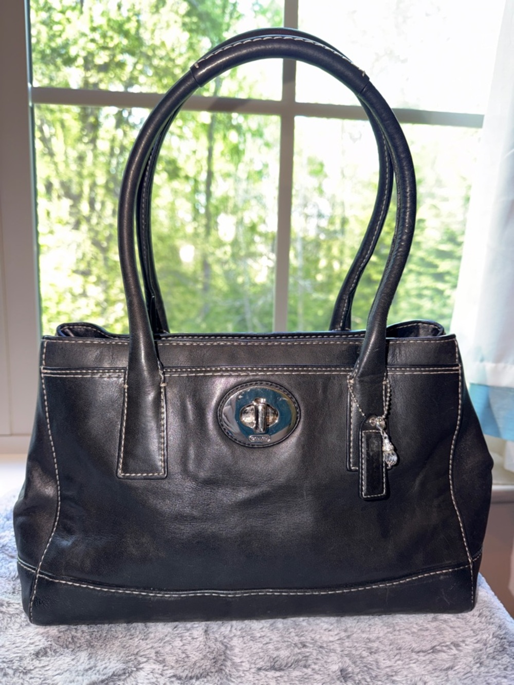 Coach black leather handbag with silver turn lock & small silver/crystal charm.